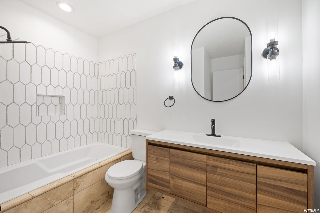 Full bathroom with vanity, toilet, tiled shower / bath, and tile flooring