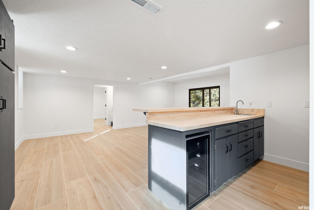 Kitchen with sink, light hardwood / wood-style floors, and beverage cooler