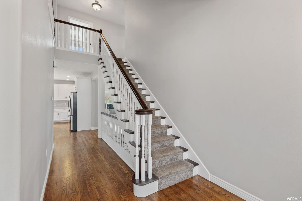 Stairs featuring dark hardwood / wood-style flooring, a wealth of natural light, and a towering ceiling