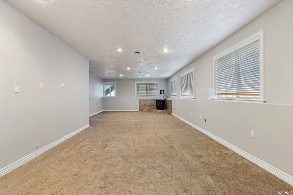Unfurnished living room featuring a textured ceiling and light carpet