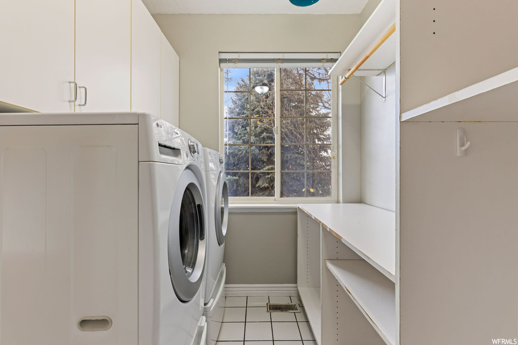 Laundry room featuring cabinets, washer and clothes dryer, and light tile floors