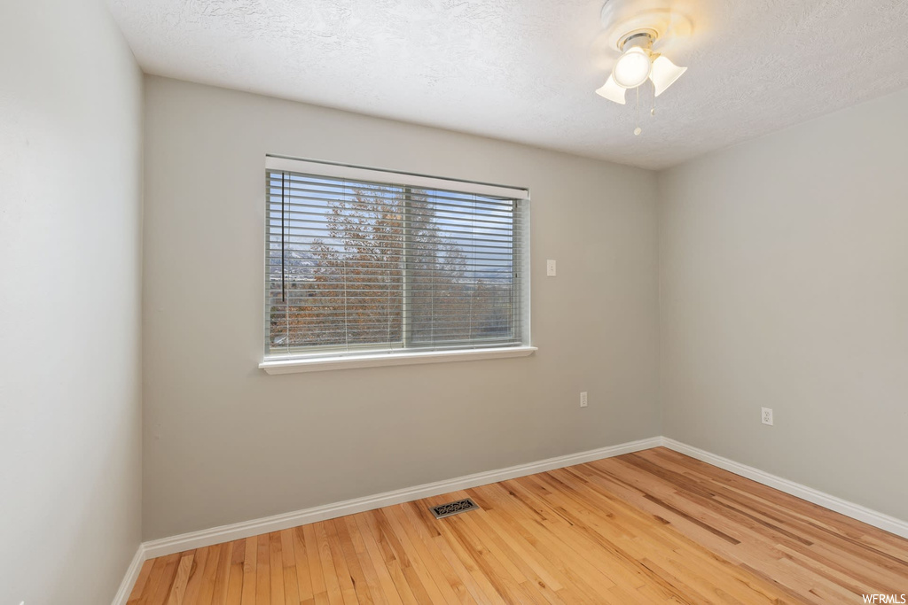 Spare room with a textured ceiling and light hardwood / wood-style flooring