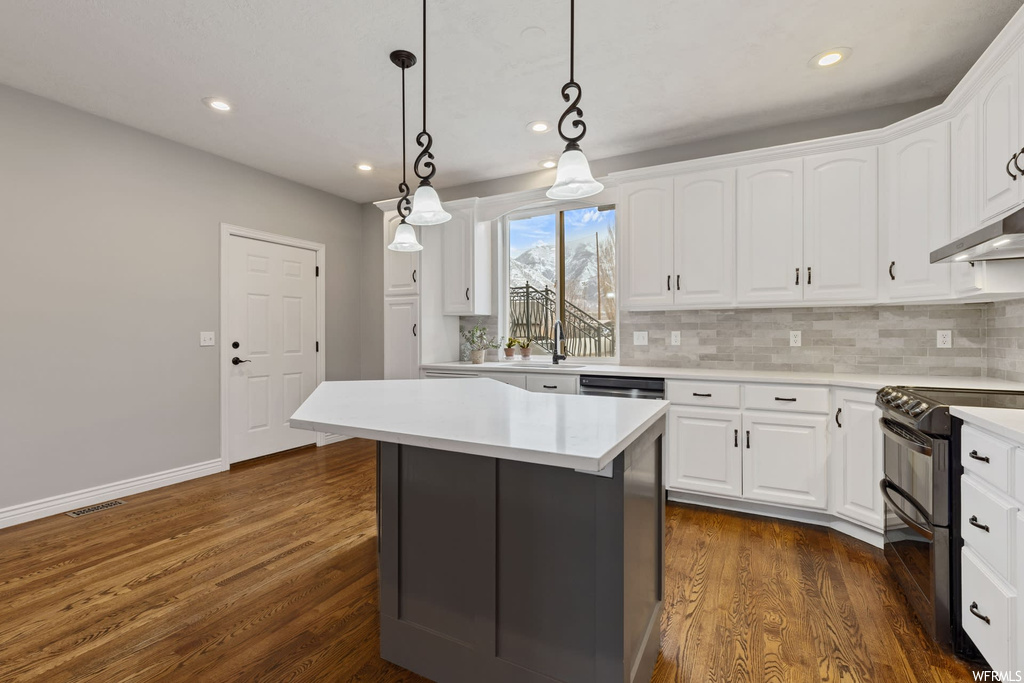 Kitchen featuring electric range oven, white cabinetry, pendant lighting, and dark wood-type flooring