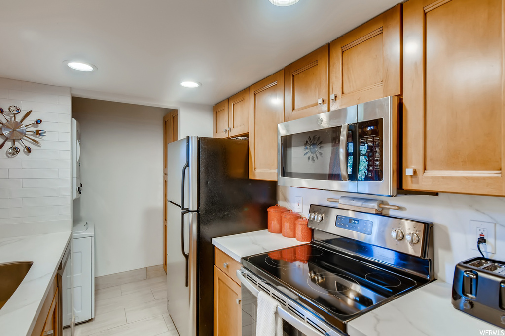 Kitchen featuring sink, washer / clothes dryer, stainless steel appliances, and light tile floors