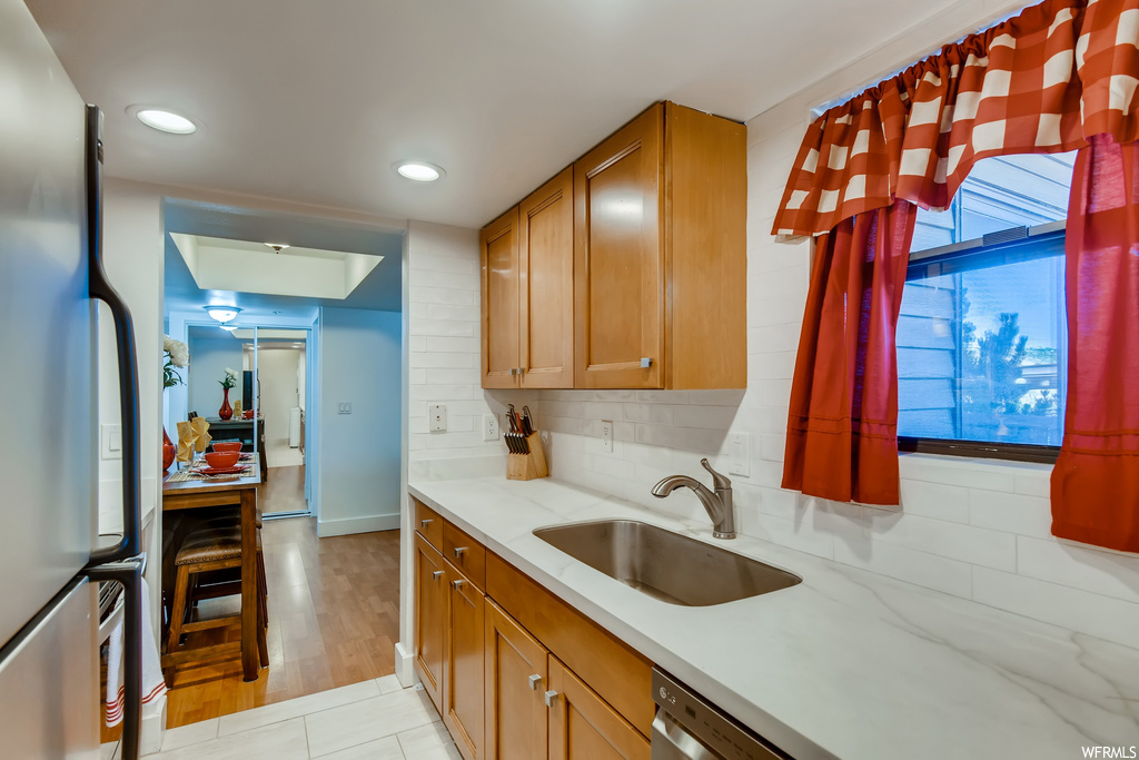 Kitchen featuring stainless steel refrigerator, tasteful backsplash, sink, and light wood-type flooring