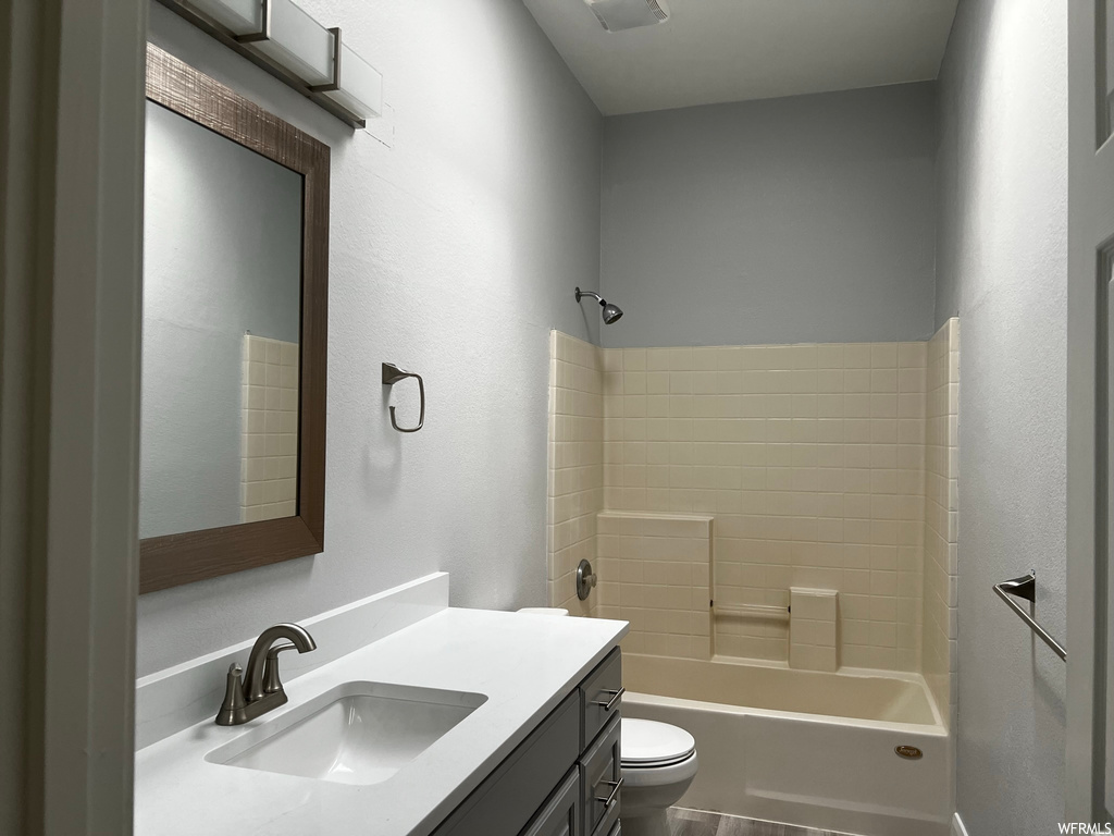 Full bathroom featuring tiled shower / bath, toilet, and vanity with extensive cabinet space