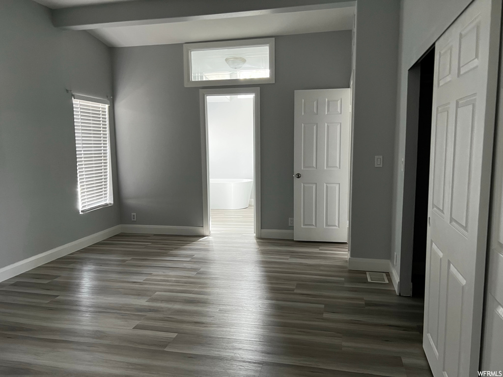Spare room featuring dark hardwood / wood-style flooring and beamed ceiling