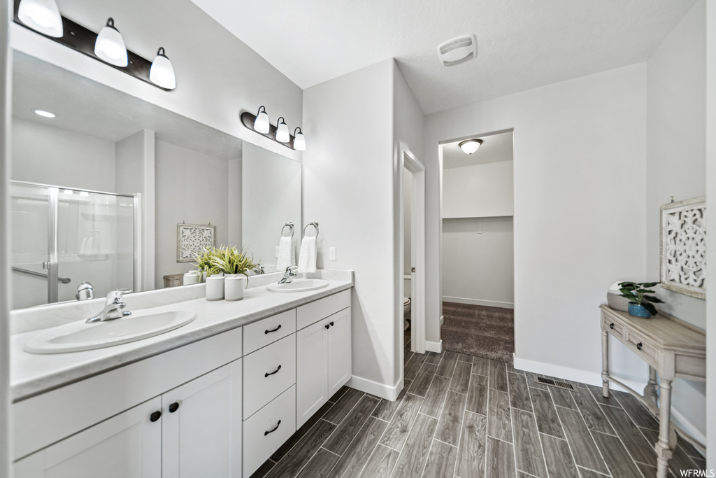 Bathroom featuring vanity with extensive cabinet space, double sink, and walk in shower
