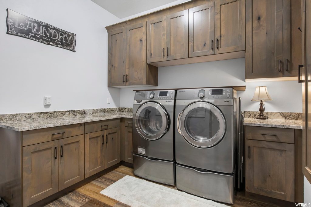 Clothes washing area with dark hardwood / wood-style floors, cabinets, and separate washer and dryer