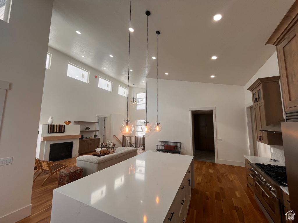Kitchen featuring range with two ovens, a center island, dark hardwood / wood-style floors, a high ceiling, and pendant lighting