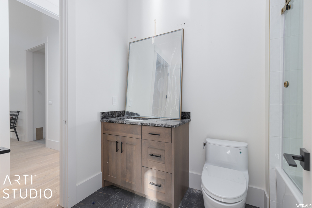 Full bathroom with bath / shower combo with glass door, vanity, toilet, and hardwood / wood-style floors