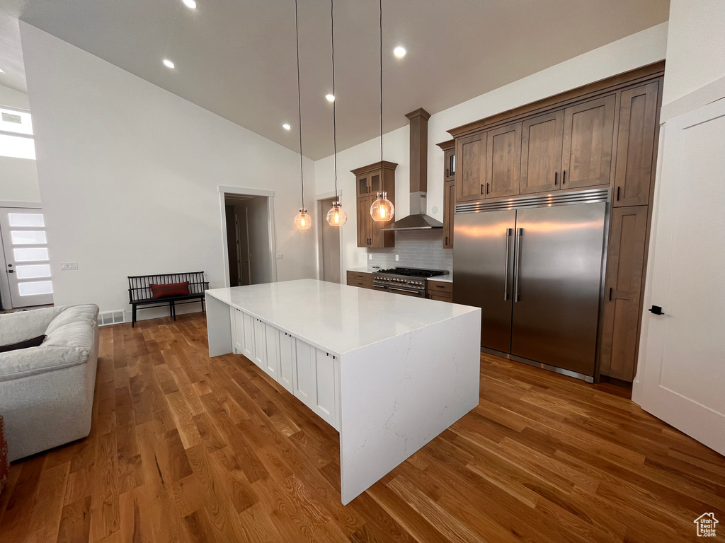 Kitchen with dark hardwood / wood-style floors, hanging light fixtures, high quality appliances, and backsplash
