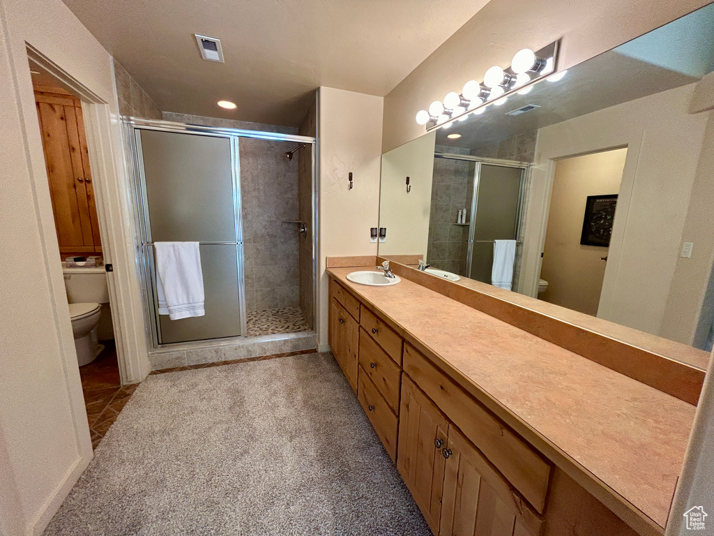 Bathroom featuring vanity, toilet, and a shower with shower door