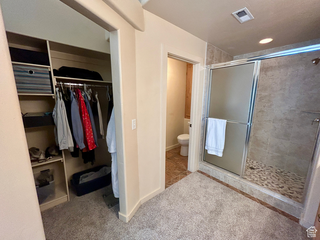 Bathroom with walk in shower, tile flooring, and toilet