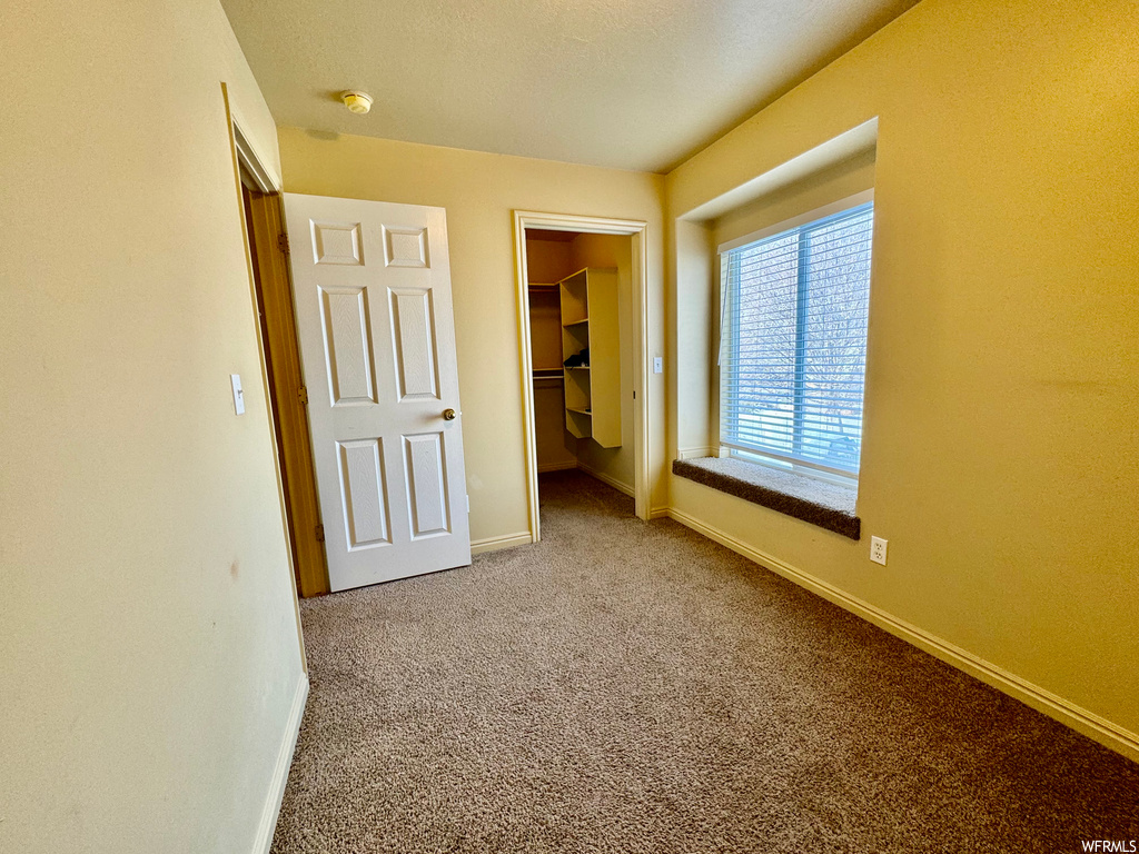 Unfurnished bedroom featuring light colored carpet, a closet, and a spacious closet
