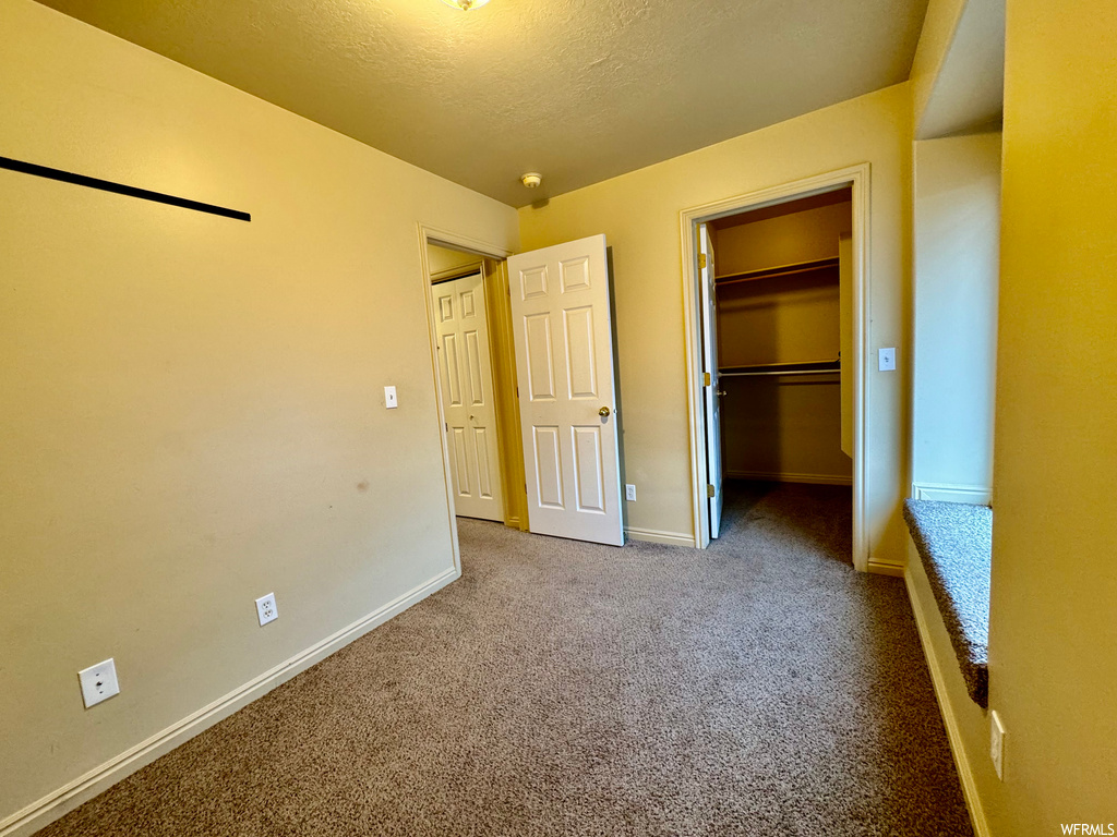Unfurnished bedroom with light carpet, a closet, and a spacious closet