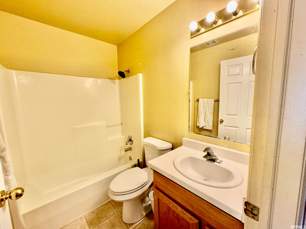 Full bathroom with tile flooring, toilet, vanity with extensive cabinet space, and  shower combination