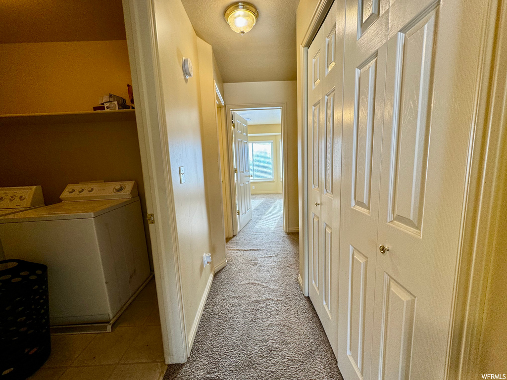 Hallway featuring washer and clothes dryer and light tile floors