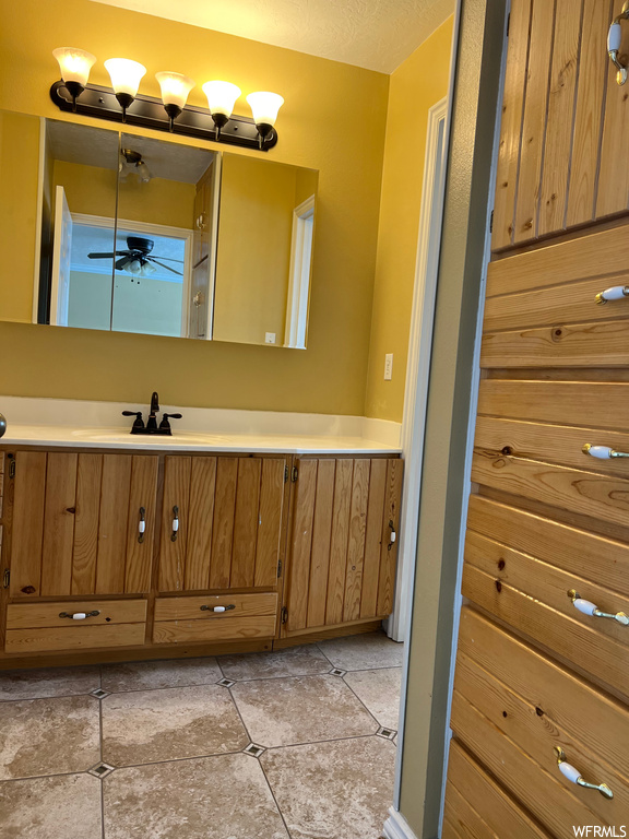 Bathroom with tile floors, vanity with extensive cabinet space, and ceiling fan