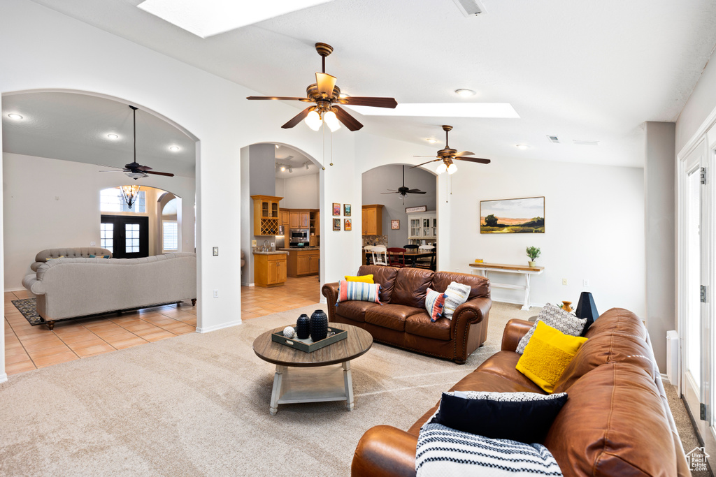 Living room featuring vaulted ceiling, light colored carpet, and ceiling fan