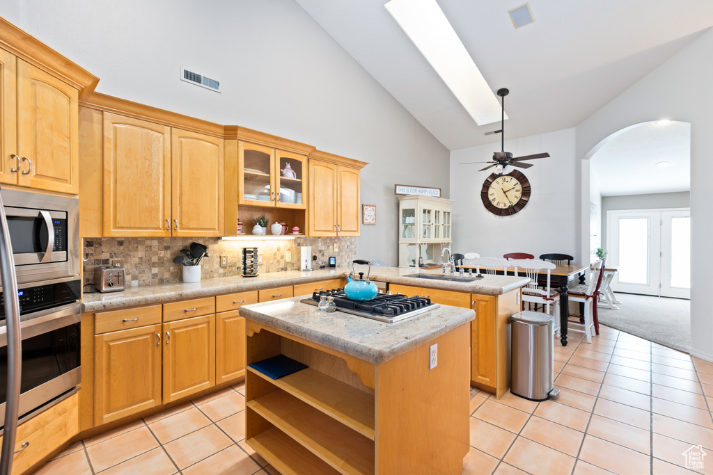 Kitchen with stainless steel appliances, tasteful backsplash, light tile flooring, and a center island