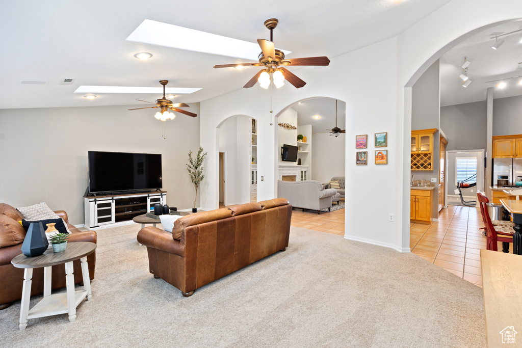 Living room featuring rail lighting, light colored carpet, lofted ceiling, and ceiling fan