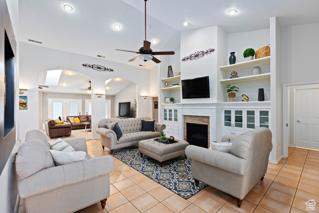 Tiled living room featuring built in features, high vaulted ceiling, and ceiling fan