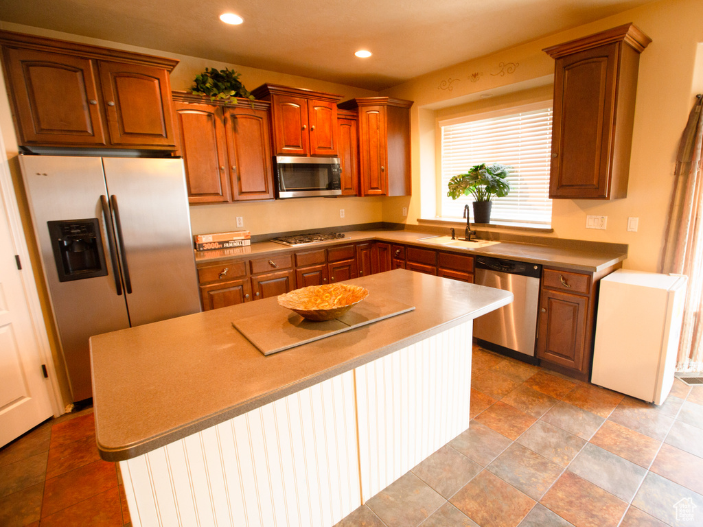 Kitchen with sink, stainless steel appliances, a kitchen island, and light tile floors
