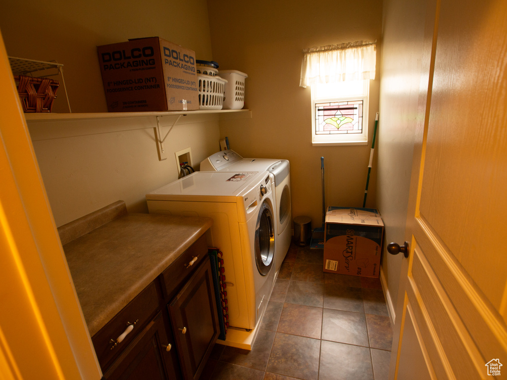 Clothes washing area featuring dark tile flooring, cabinets, washing machine and dryer, and washer hookup