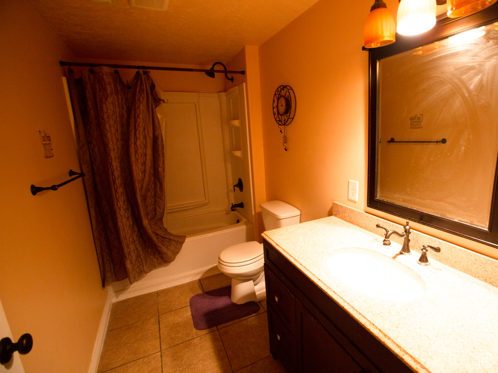 Full bathroom with toilet, vanity with extensive cabinet space, shower / bath combination, tile flooring, and a textured ceiling