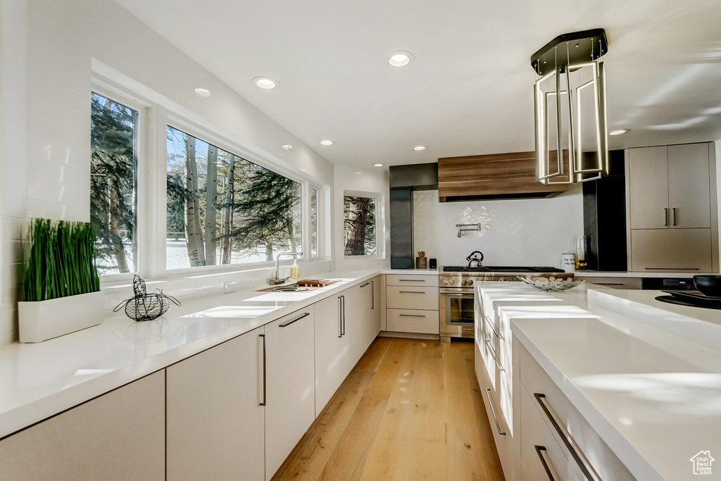 Kitchen featuring light hardwood / wood-style flooring, white cabinets, sink, and range with two ovens
