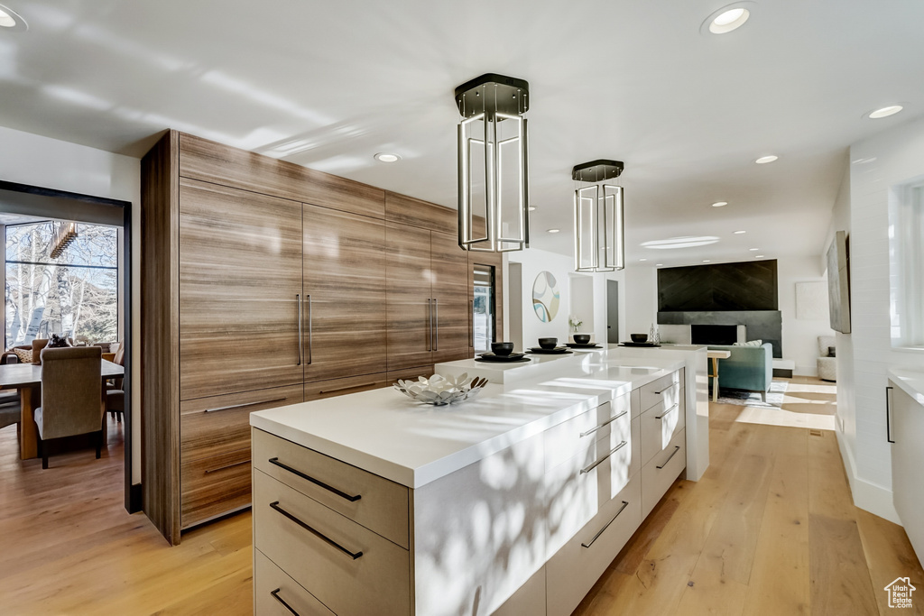Kitchen with a center island, light hardwood / wood-style flooring, and hanging light fixtures