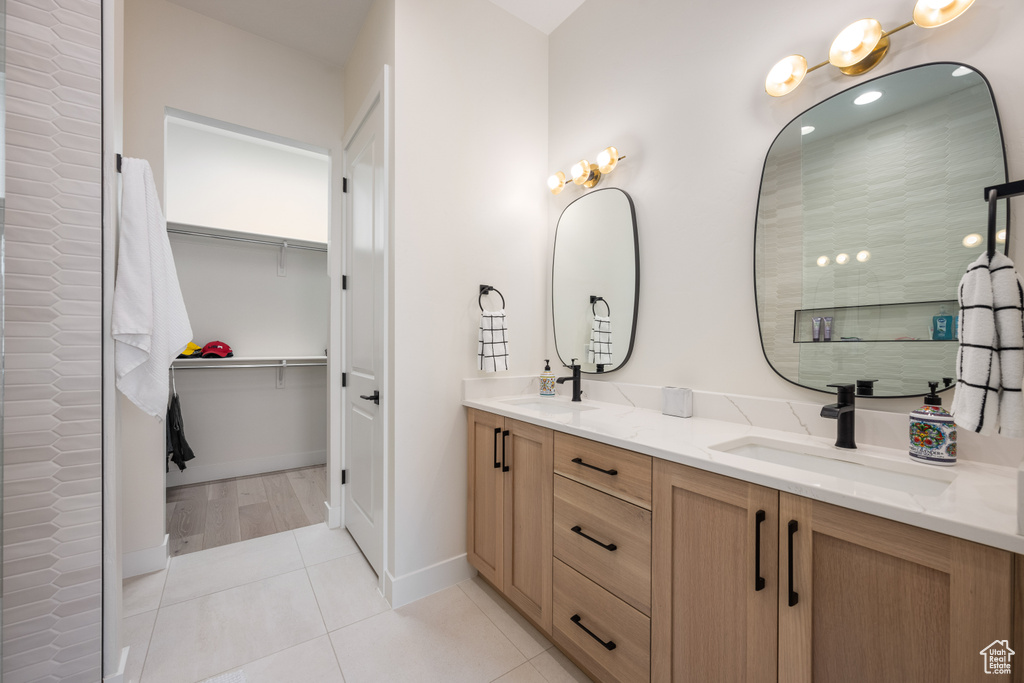 Bathroom with dual sinks, large vanity, and tile flooring