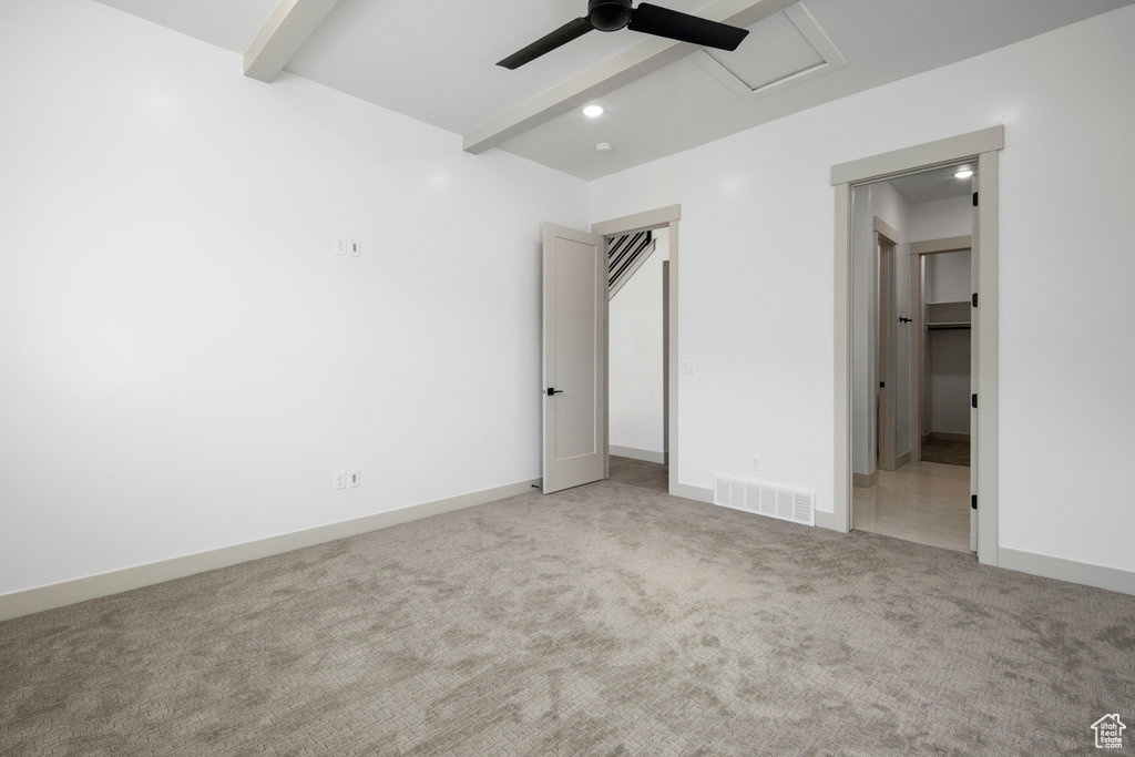 Unfurnished bedroom featuring light carpet, beam ceiling, and ceiling fan