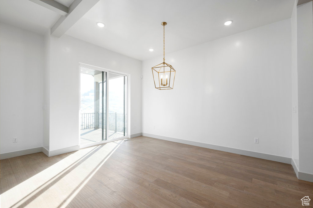 Unfurnished room with beam ceiling, a chandelier, and hardwood / wood-style flooring