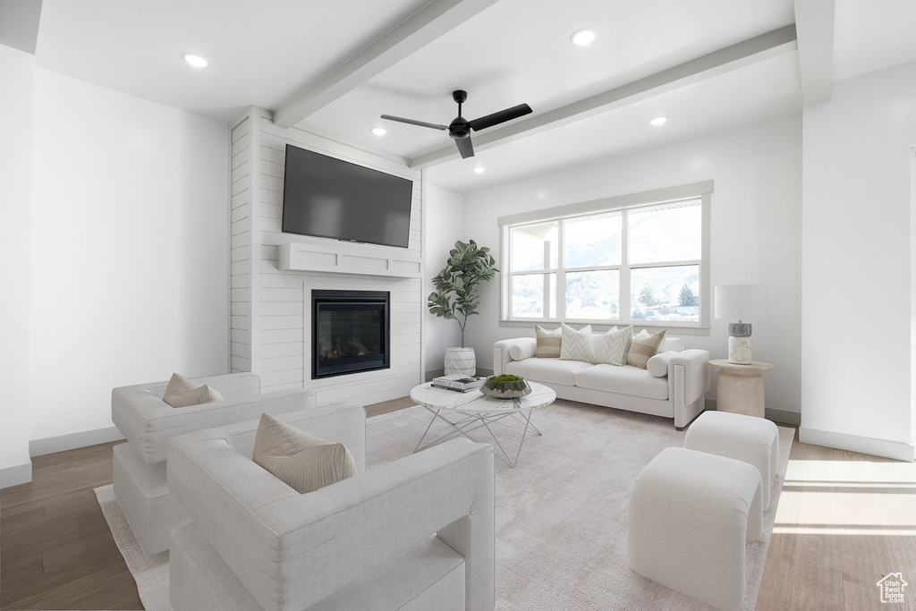 Living room featuring beam ceiling, ceiling fan, hardwood / wood-style flooring, and a fireplace