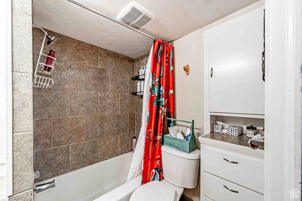 Full bathroom featuring vanity, shower / bath combination with curtain, and toilet