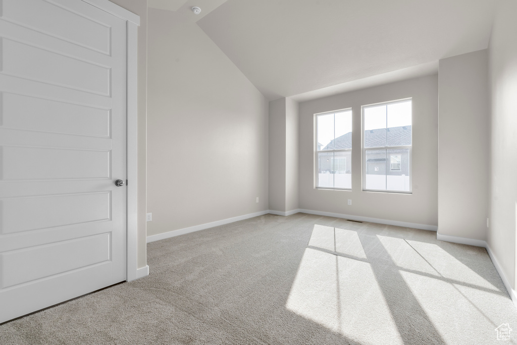 Empty room featuring light carpet and lofted ceiling
