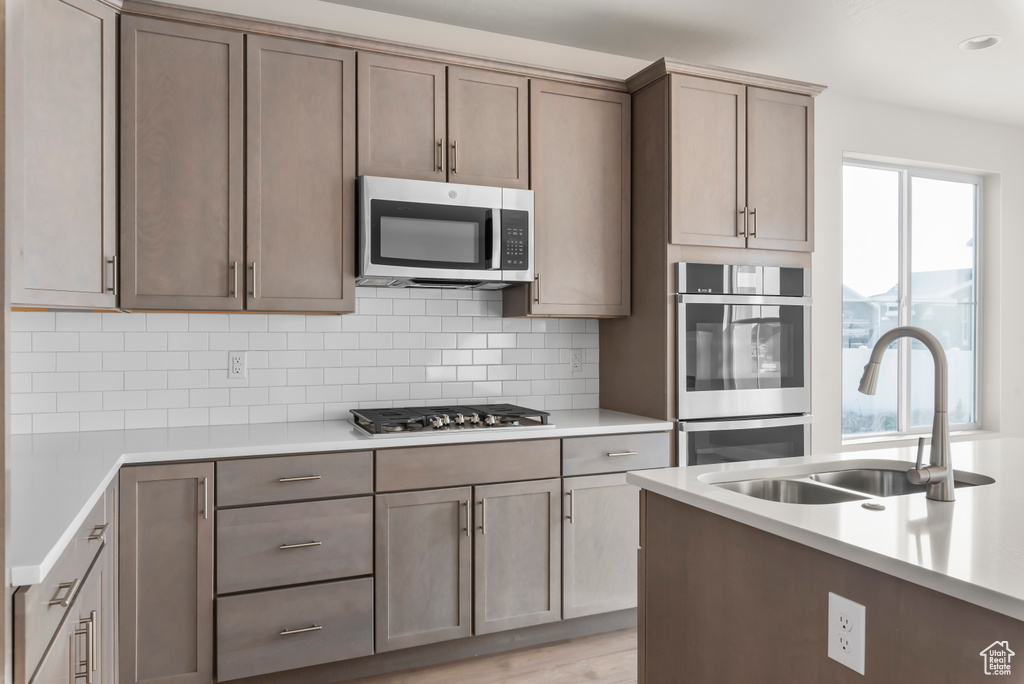 Kitchen with plenty of natural light, stainless steel appliances, tasteful backsplash, and light hardwood / wood-style floors