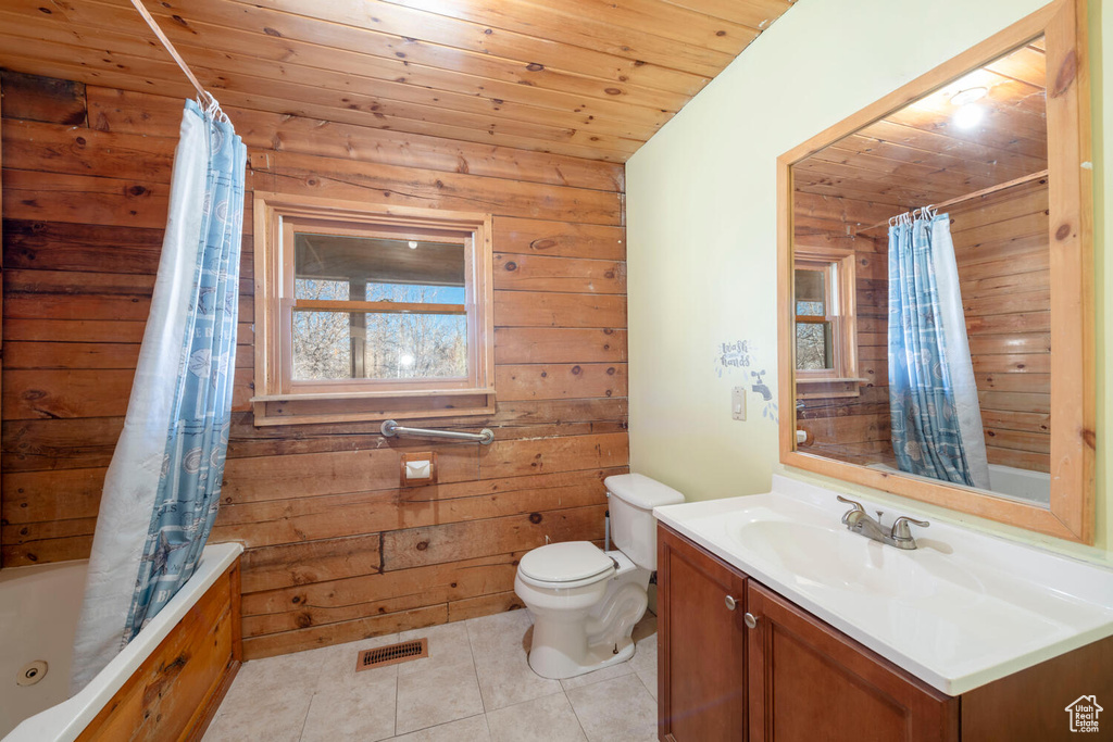 Full bathroom with vanity, wooden walls, shower / bath combo with shower curtain, wood ceiling, and tile flooring