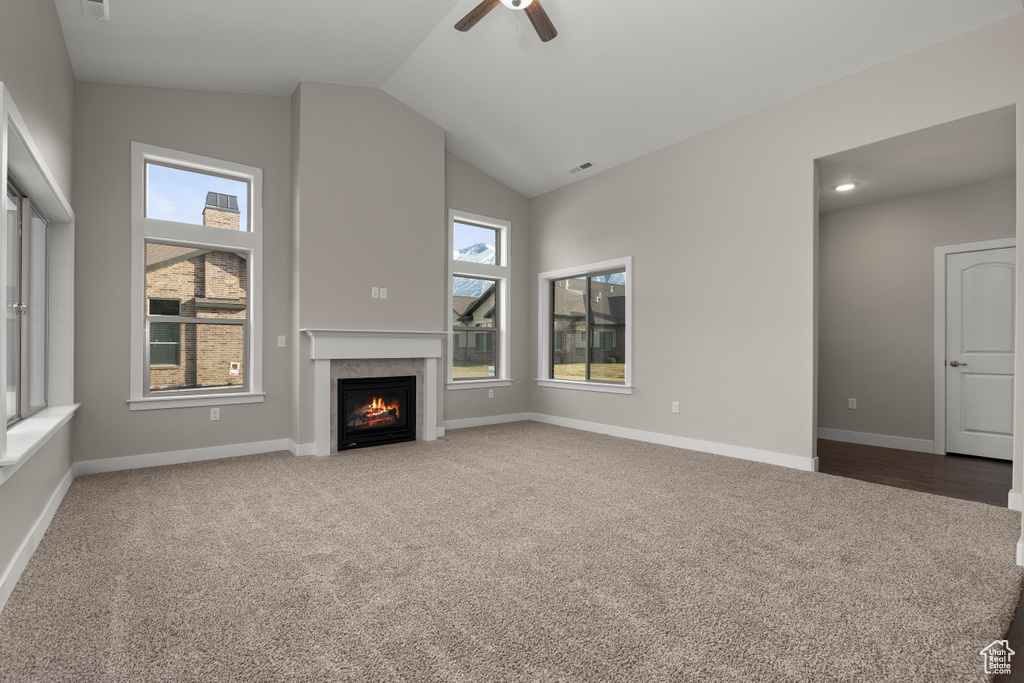 Unfurnished living room with light carpet, ceiling fan, and vaulted ceiling