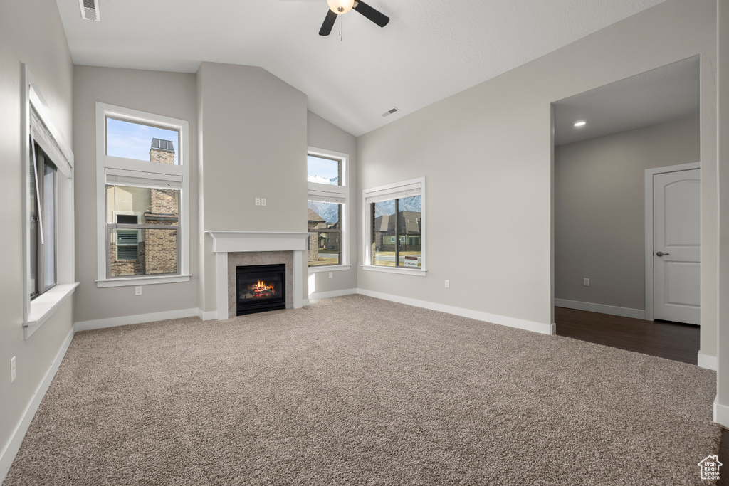 Unfurnished living room with vaulted ceiling, dark colored carpet, and ceiling fan