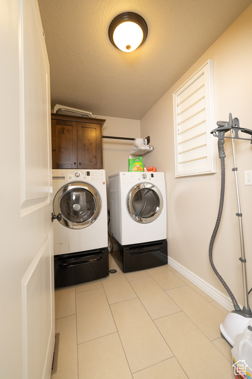 Laundry area with cabinets, washer and dryer, and light tile floors