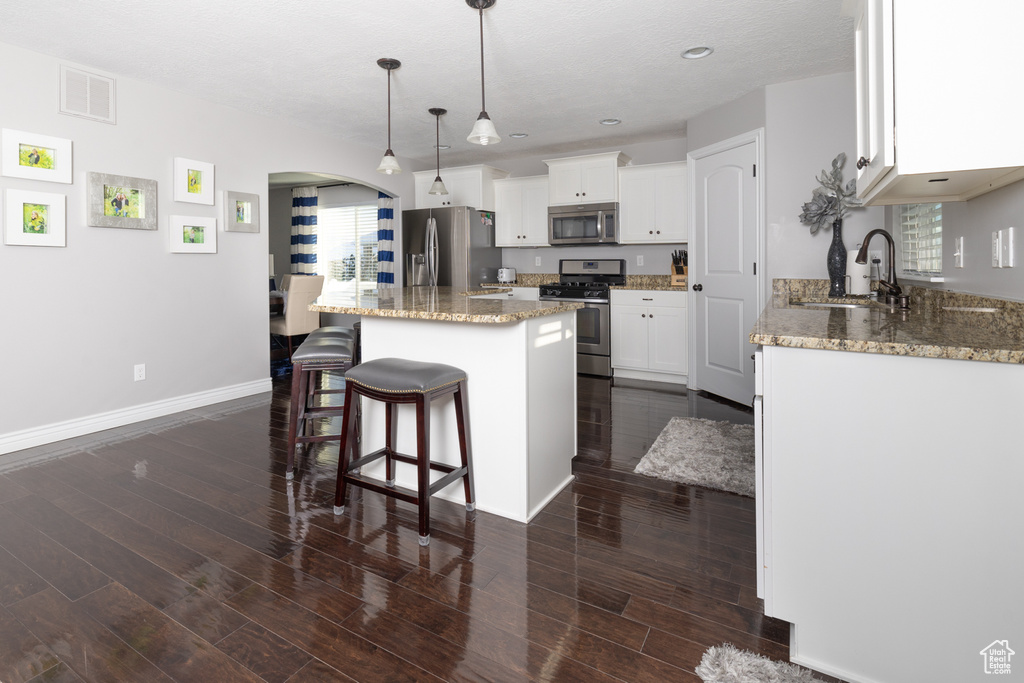 Kitchen featuring dark hardwood / wood-style flooring, a breakfast bar area, a center island, stainless steel appliances, and sink
