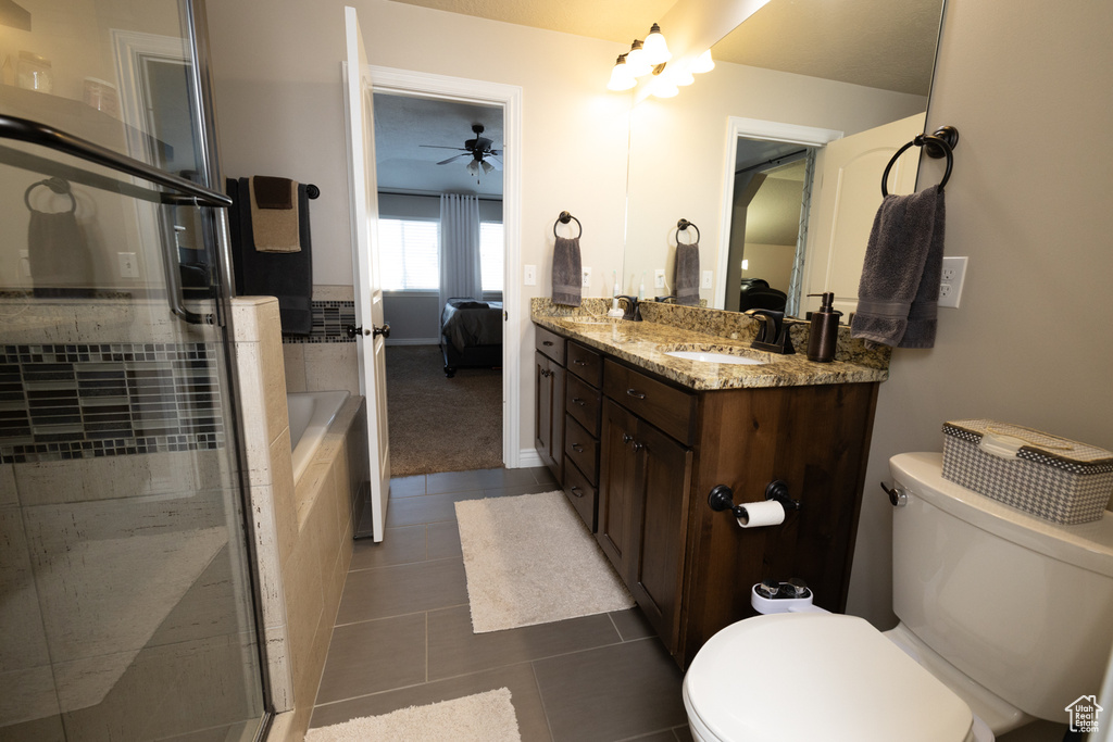 Full bathroom with tile floors, toilet, vanity, and ceiling fan