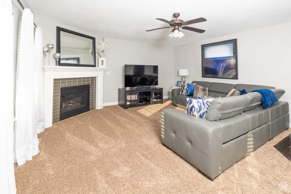 Living room featuring light carpet, a fireplace, and ceiling fan