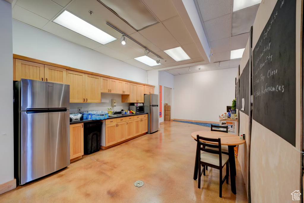 Kitchen featuring stainless steel appliances, light brown cabinets, a breakfast bar area, and a drop ceiling