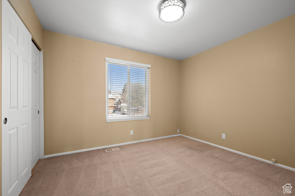 Unfurnished bedroom with light carpet and a closet