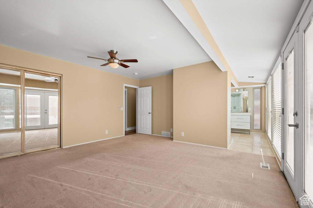 Spare room featuring plenty of natural light, light colored carpet, french doors, and ceiling fan