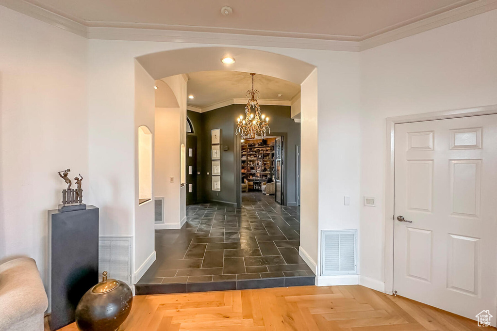 Corridor with a notable chandelier, dark parquet floors, and crown molding